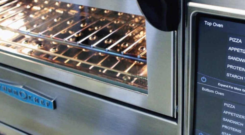 A chef carefully closing a commercial speed oven door to prevent hardware damage.